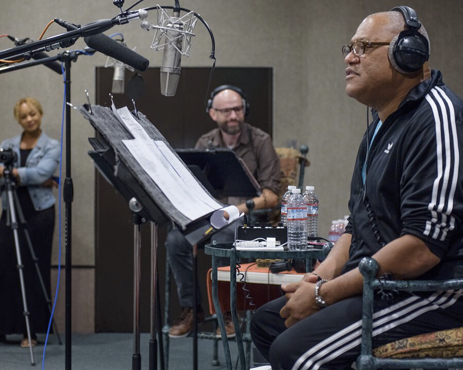 Laurence Fishburne sits at a microphone, recording "Bronzeville" from a script, as K.C. Wayland and another crew member look on